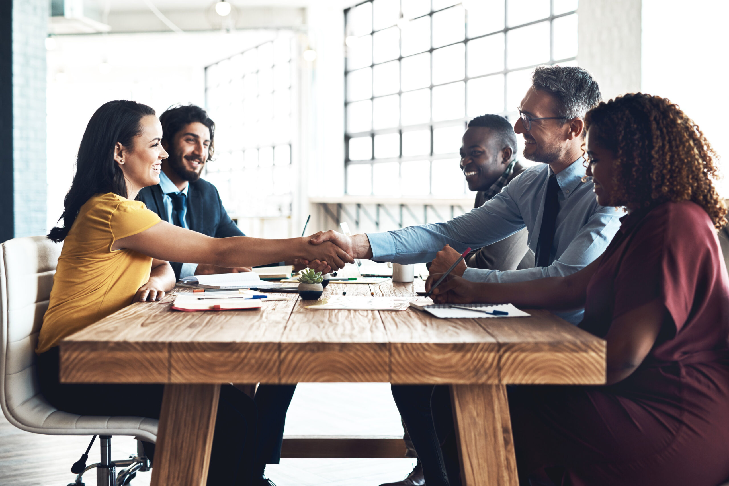 collaborative team shakes hands across a table after partnership success
